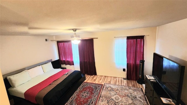 bedroom with ceiling fan, a textured ceiling, and light hardwood / wood-style flooring