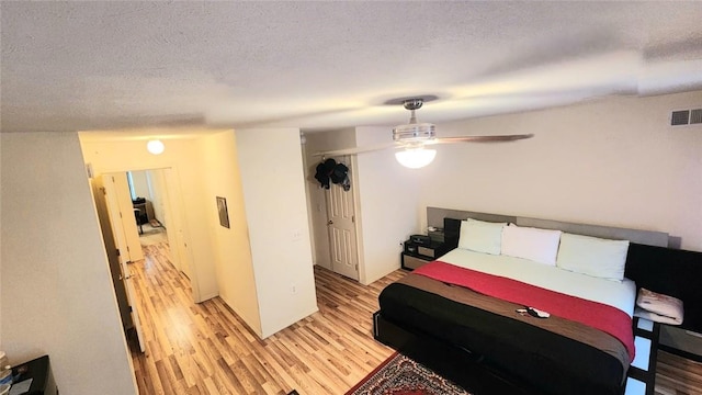 bedroom featuring ceiling fan, light wood-type flooring, a textured ceiling, and a closet