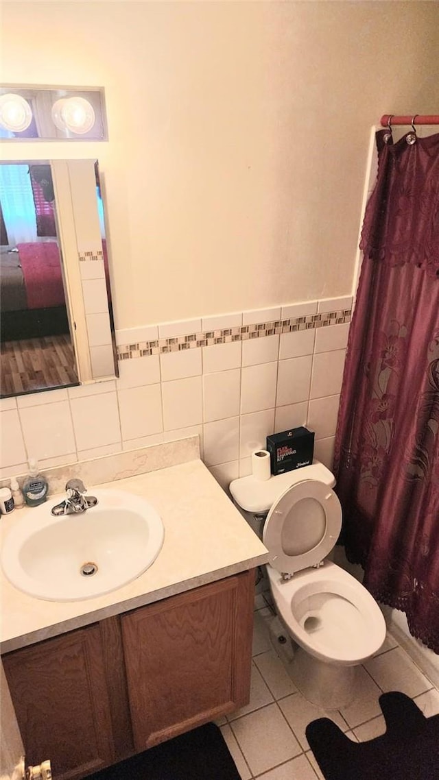 bathroom featuring a shower with shower curtain, vanity, tile walls, tile patterned flooring, and toilet