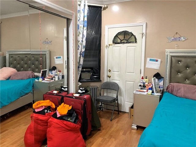 bedroom featuring light wood-type flooring and crown molding