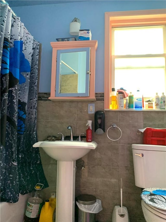 bathroom featuring toilet and tile walls