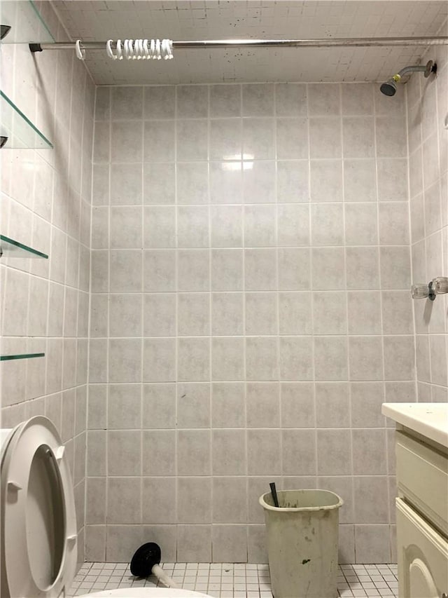 bathroom with tiled shower, vanity, and tile patterned flooring