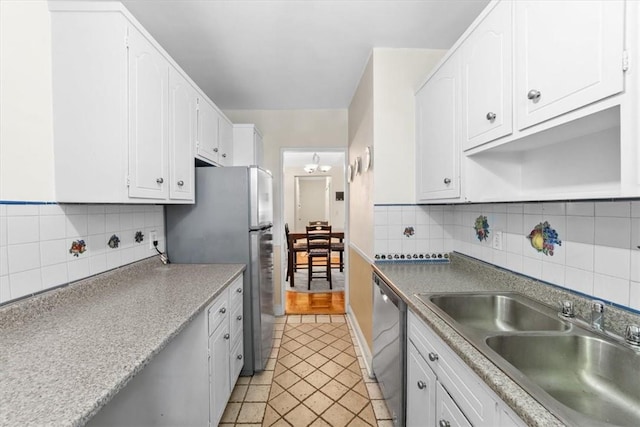 kitchen featuring white cabinets, appliances with stainless steel finishes, decorative backsplash, and sink