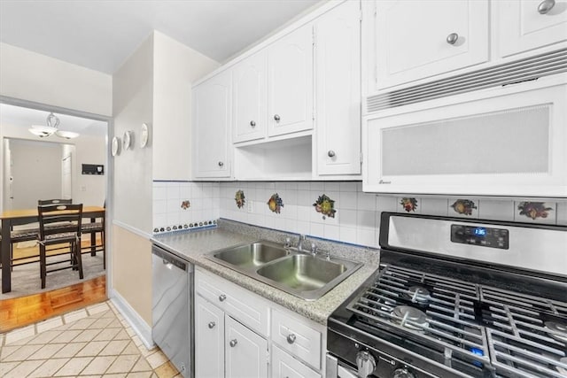 kitchen with sink, backsplash, light hardwood / wood-style floors, white cabinets, and appliances with stainless steel finishes