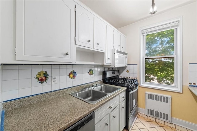 kitchen featuring white cabinets, radiator, appliances with stainless steel finishes, and tasteful backsplash