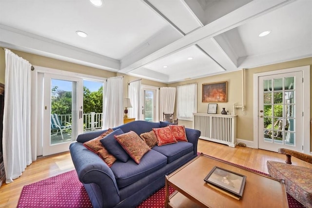 living room with beam ceiling, a healthy amount of sunlight, coffered ceiling, and light hardwood / wood-style floors