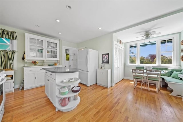 kitchen featuring ceiling fan, a center island, white refrigerator, white cabinets, and light wood-type flooring