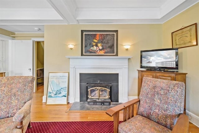 living area with beam ceiling, wood-type flooring, and ornamental molding