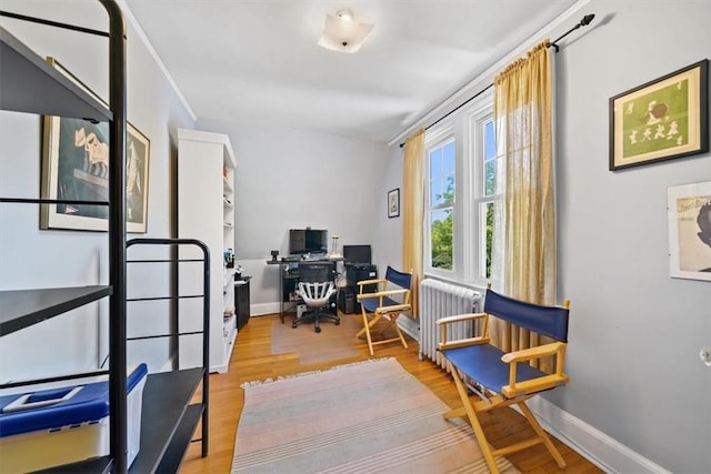 home office with light hardwood / wood-style flooring and radiator