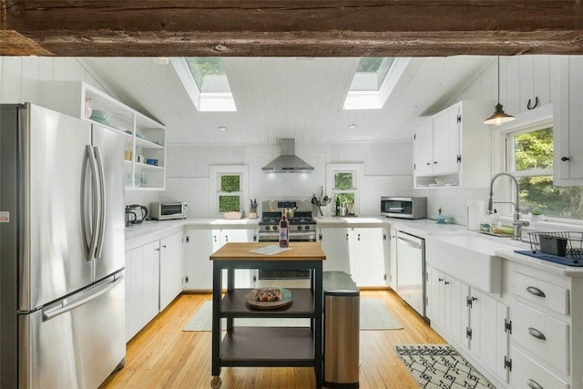 kitchen featuring white cabinets, light hardwood / wood-style floors, wall chimney range hood, and appliances with stainless steel finishes