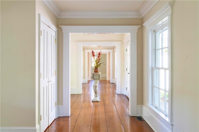 hallway with light wood-type flooring, plenty of natural light, and crown molding