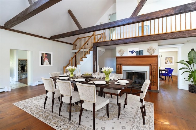 dining space with hardwood / wood-style floors, beamed ceiling, high vaulted ceiling, and a baseboard radiator