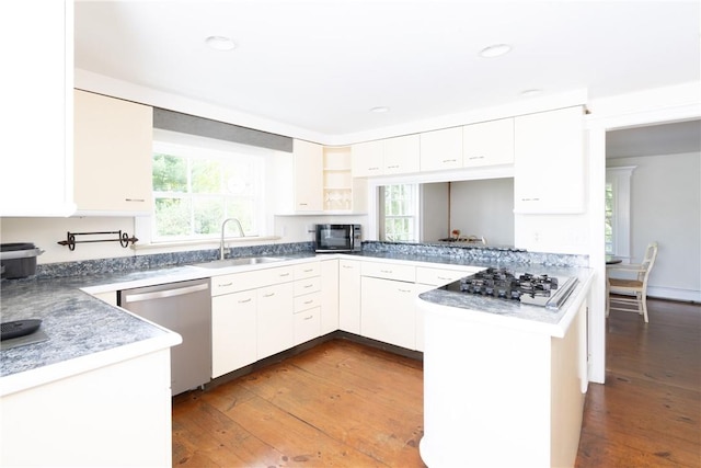 kitchen featuring white cabinets, kitchen peninsula, stainless steel appliances, and dark wood-type flooring