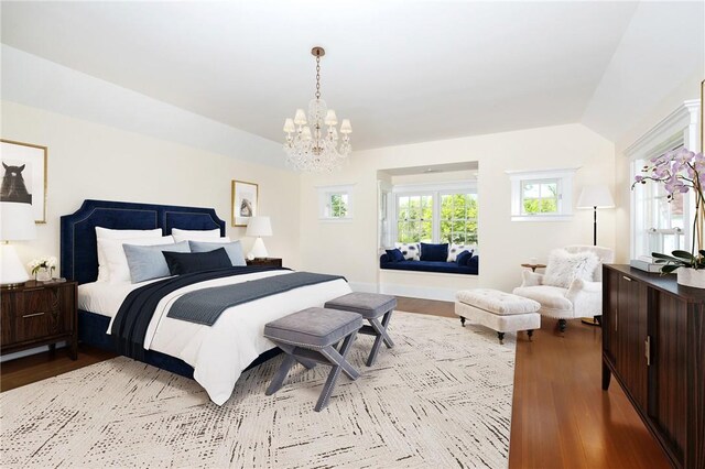 bedroom featuring a chandelier, light hardwood / wood-style floors, and lofted ceiling