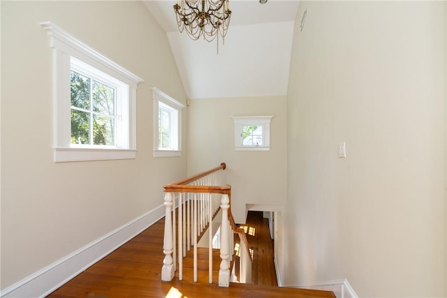 stairs featuring lofted ceiling, a notable chandelier, and hardwood / wood-style flooring