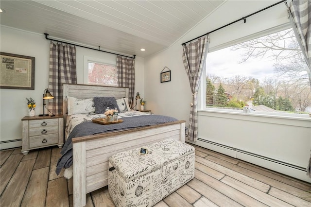 bedroom with light hardwood / wood-style floors, baseboard heating, and multiple windows