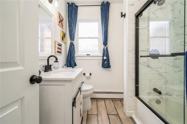 full bathroom with bath / shower combo with glass door, vanity, wood-type flooring, a baseboard radiator, and toilet