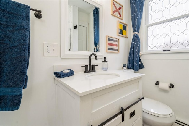 bathroom featuring vanity, a baseboard heating unit, and toilet