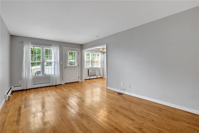 interior space with a baseboard heating unit, a wealth of natural light, a notable chandelier, and light wood-type flooring