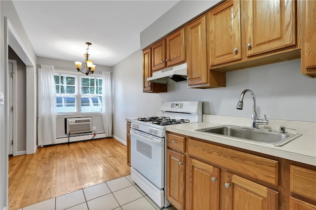 kitchen with sink, white gas range oven, light tile patterned floors, a notable chandelier, and a wall unit AC