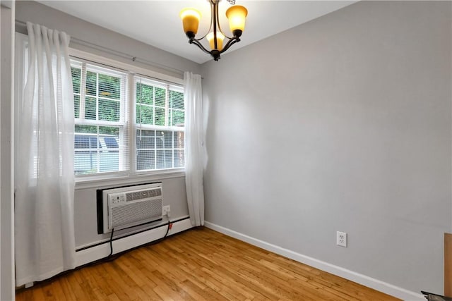 empty room featuring a wall unit AC, a healthy amount of sunlight, a chandelier, and a baseboard heating unit