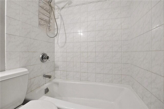 bathroom featuring toilet and tiled shower / bath