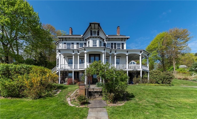 view of front of house with a balcony, covered porch, and a front lawn