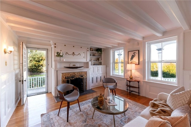 living room featuring beamed ceiling, a premium fireplace, and light hardwood / wood-style floors