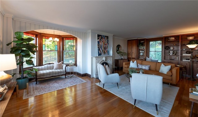 living room with a notable chandelier, crown molding, wood-type flooring, and plenty of natural light