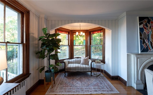 sitting room featuring ornamental molding, radiator, hardwood / wood-style floors, and an inviting chandelier