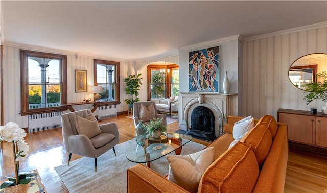 living room featuring a notable chandelier, radiator, crown molding, and light hardwood / wood-style floors