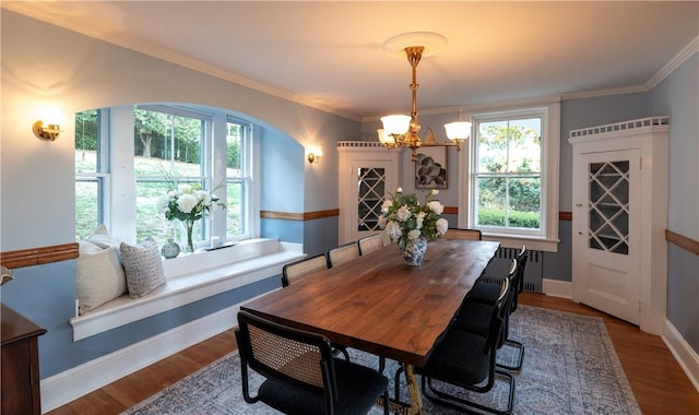 dining room with an inviting chandelier, hardwood / wood-style floors, crown molding, and radiator