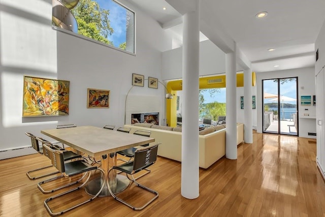 dining area featuring light wood-type flooring and a high ceiling