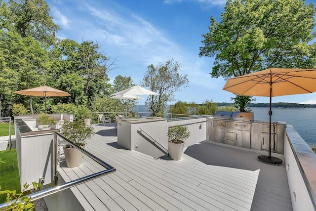 wooden deck featuring grilling area, a water view, and exterior kitchen