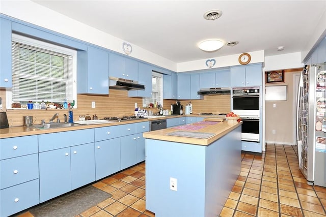 kitchen featuring blue cabinetry, sink, stainless steel appliances, light tile patterned floors, and a kitchen island