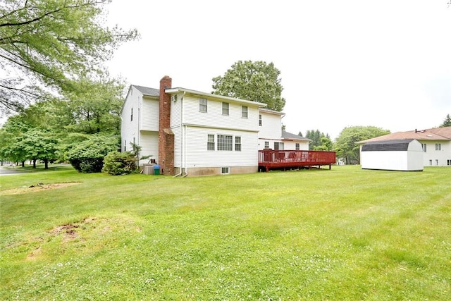 rear view of property featuring a yard, a shed, and a wooden deck