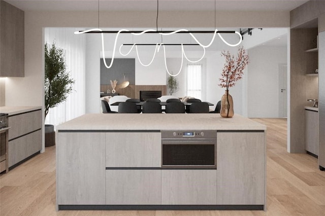 kitchen with oven, light wood-type flooring, and hanging light fixtures