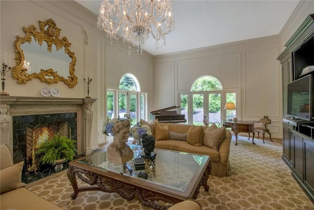 living room featuring a high end fireplace, a towering ceiling, crown molding, and a notable chandelier