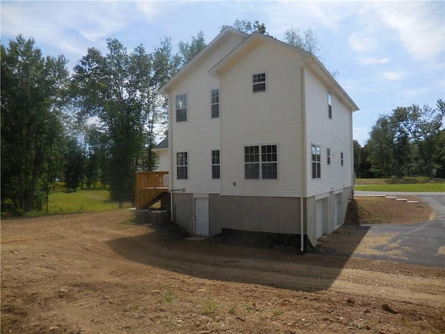 view of home's exterior with central AC unit, a deck, and a garage