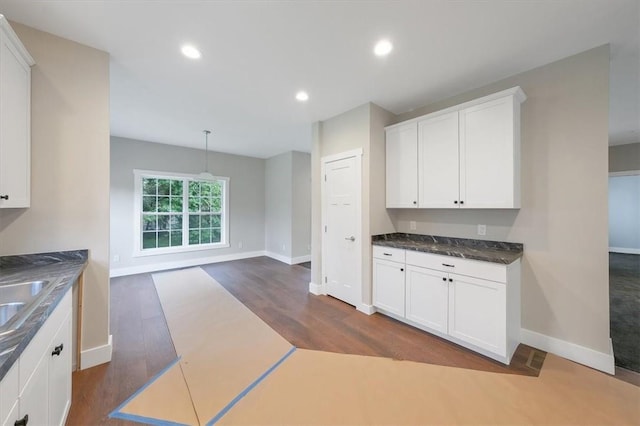 kitchen featuring dark hardwood / wood-style flooring, white cabinets, pendant lighting, and sink