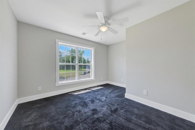 spare room featuring dark colored carpet and ceiling fan