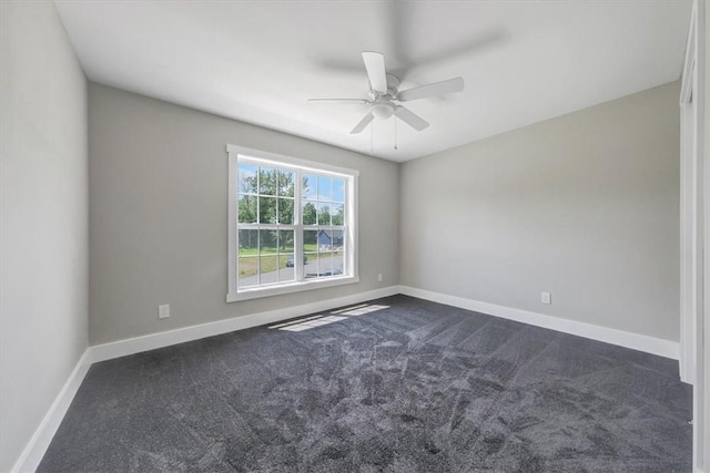 spare room featuring dark colored carpet and ceiling fan