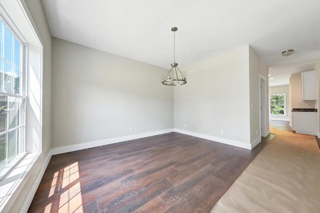 unfurnished room with dark hardwood / wood-style flooring and a notable chandelier