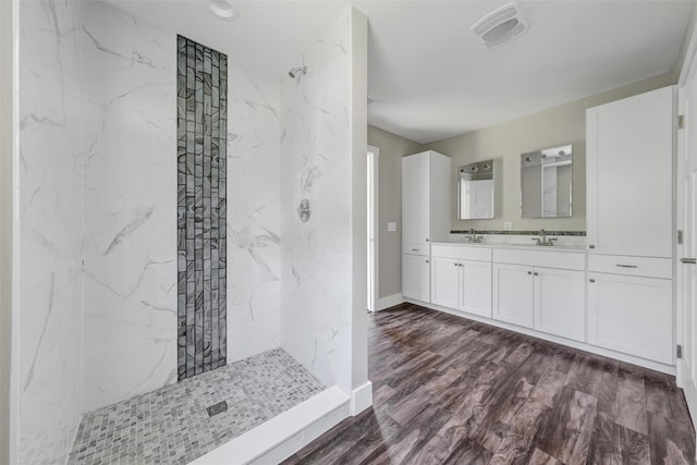 bathroom featuring a tile shower, vanity, and wood-type flooring