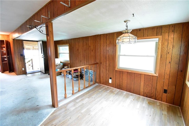 unfurnished dining area featuring wood walls and light wood-type flooring