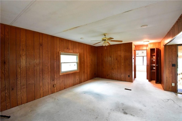 empty room featuring light colored carpet, ceiling fan, and wooden walls