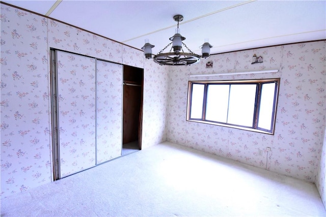 unfurnished bedroom featuring a chandelier and a closet