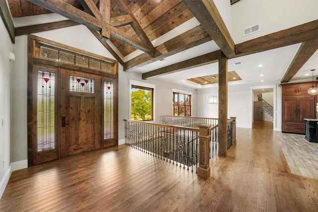 foyer entrance with beamed ceiling, wood-type flooring, and high vaulted ceiling