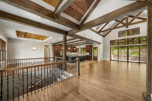 hall with an inviting chandelier, beamed ceiling, high vaulted ceiling, and light wood-type flooring