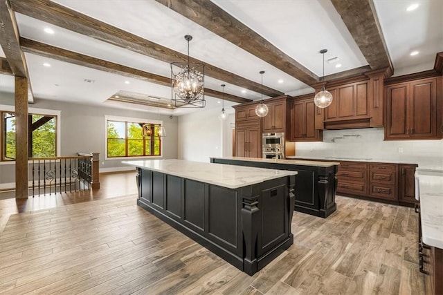 kitchen with beam ceiling, decorative light fixtures, light hardwood / wood-style flooring, and a large island